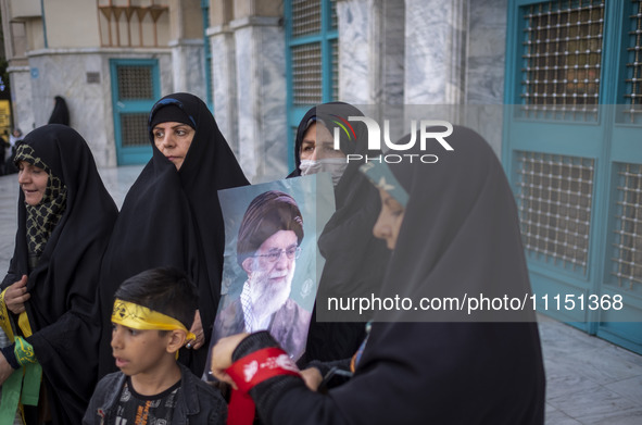 A veiled Iranian woman is holding a portrait of Iran's Supreme Leader, Ayatollah Ali Khamenei, while celebrating the IRGC UAV and missile at...