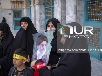 A veiled Iranian woman is holding a portrait of Iran's Supreme Leader, Ayatollah Ali Khamenei, while celebrating the IRGC UAV and missile at...