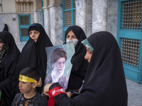 A veiled Iranian woman is holding a portrait of Iran's Supreme Leader, Ayatollah Ali Khamenei, while celebrating the IRGC UAV and missile at...