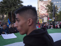 A model of Iran's first-ever hypersonic missile, Fattah (R), is being displayed next to an anti-Israeli mural while men stand behind a huge...