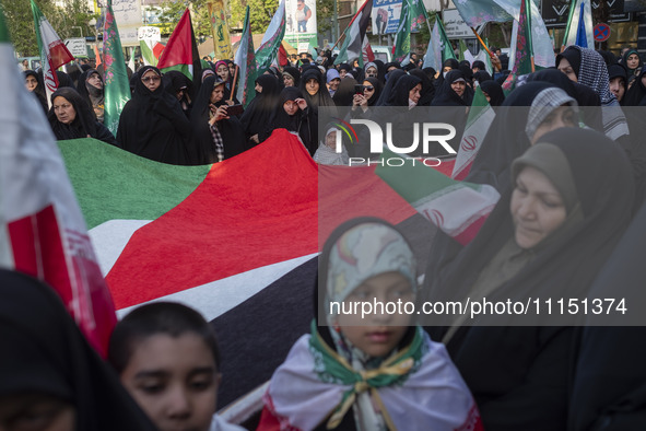 Veiled Iranian women are standing around a huge Palestinian flag during a gathering to celebrate the IRGC UAV and missile attack against Isr...