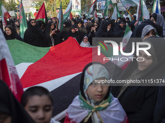 Veiled Iranian women are standing around a huge Palestinian flag during a gathering to celebrate the IRGC UAV and missile attack against Isr...