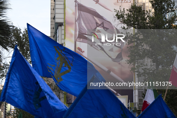 Veiled Iranian women are waving flags of the Islamic Revolutionary Guard Corps under an anti-Israeli mural during a gathering to celebrate t...