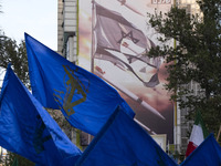 Veiled Iranian women are waving flags of the Islamic Revolutionary Guard Corps under an anti-Israeli mural during a gathering to celebrate t...