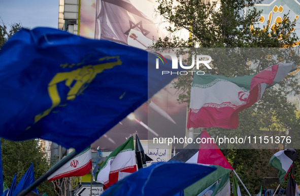 Veiled Iranian women are waving Iranian flags and Islamic Revolutionary Guard Corps flags under an anti-Israeli mural as they gather to cele...