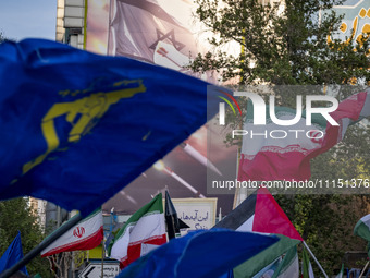 Veiled Iranian women are waving Iranian flags and Islamic Revolutionary Guard Corps flags under an anti-Israeli mural as they gather to cele...