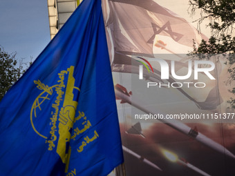 An Iranian man is waving a flag of the Islamic Revolutionary Guard Corps next to an anti-Israeli mural while celebrating the IRGC UAV and mi...