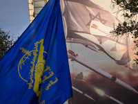 An Iranian man is waving a flag of the Islamic Revolutionary Guard Corps next to an anti-Israeli mural while celebrating the IRGC UAV and mi...