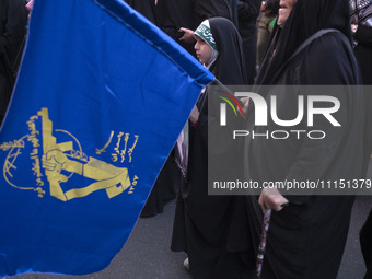 A young veiled Iranian girl is standing next to a flag of the Islamic Revolutionary Guard Corps, celebrating the IRGC UAV and missile attack...