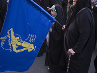 A young veiled Iranian girl is standing next to a flag of the Islamic Revolutionary Guard Corps, celebrating the IRGC UAV and missile attack...