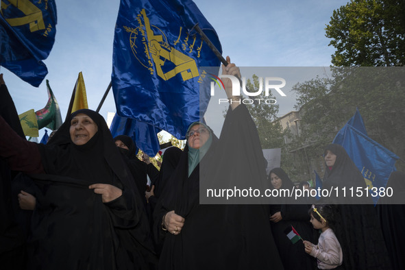 Veiled Iranian women are waving flags of the Islamic Revolutionary Guard Corps during a gathering to celebrate the IRGC UAV and missile atta...