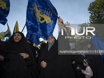 Veiled Iranian women are waving flags of the Islamic Revolutionary Guard Corps during a gathering to celebrate the IRGC UAV and missile atta...