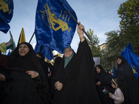 Veiled Iranian women are waving flags of the Islamic Revolutionary Guard Corps during a gathering to celebrate the IRGC UAV and missile atta...