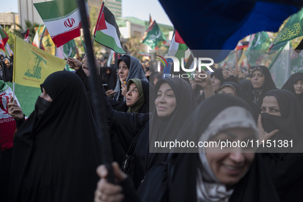 Veiled women are waving Iranian and Palestinian flags during a gathering to celebrate the IRGC UAV and missile attack against Israel, in Teh...