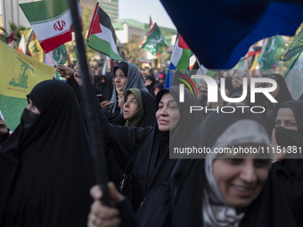 Veiled women are waving Iranian and Palestinian flags during a gathering to celebrate the IRGC UAV and missile attack against Israel, in Teh...