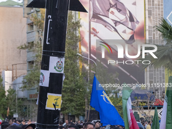 Unidentified men are holding a model of Iran's first-ever hypersonic missile, Fattah, next to an anti-Israeli mural during a gathering to ce...