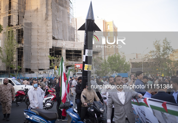 Two unidentified men are carrying a model of Iran's first-ever hypersonic missile, Fattah, by a motorcycle during a gathering to celebrate t...