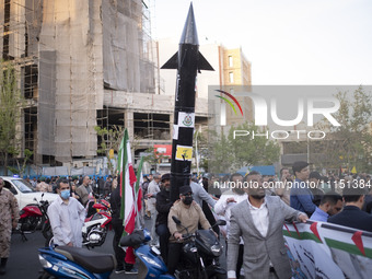 Two unidentified men are carrying a model of Iran's first-ever hypersonic missile, Fattah, by a motorcycle during a gathering to celebrate t...