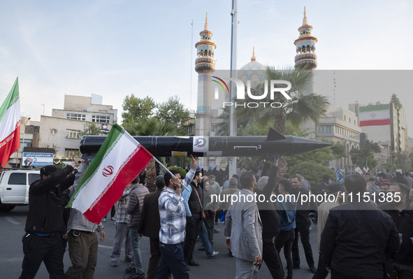 Unidentified men are carrying a model of Iran's first-ever hypersonic missile, Fattah, past a mosque during a gathering to celebrate the IRG...