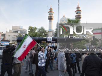 Unidentified men are carrying a model of Iran's first-ever hypersonic missile, Fattah, past a mosque during a gathering to celebrate the IRG...