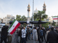 Unidentified men are carrying a model of Iran's first-ever hypersonic missile, Fattah, past a mosque during a gathering to celebrate the IRG...