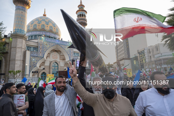 Unidentified men are carrying a model of Iran's first-ever hypersonic missile, Fattah, past a mosque during a gathering to celebrate the IRG...