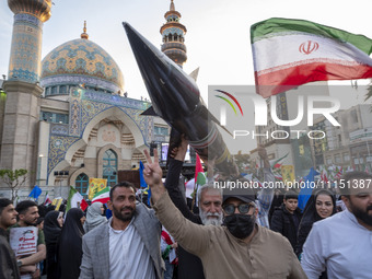 Unidentified men are carrying a model of Iran's first-ever hypersonic missile, Fattah, past a mosque during a gathering to celebrate the IRG...