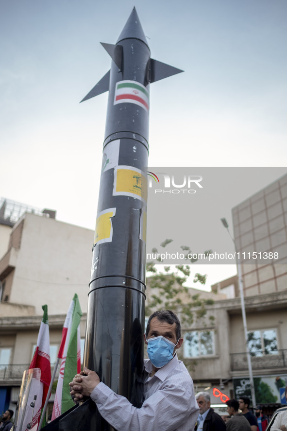 An unidentified man is holding a model of Iran's first-ever hypersonic missile, Fattah, during a gathering to celebrate the IRGC UAV and mis...