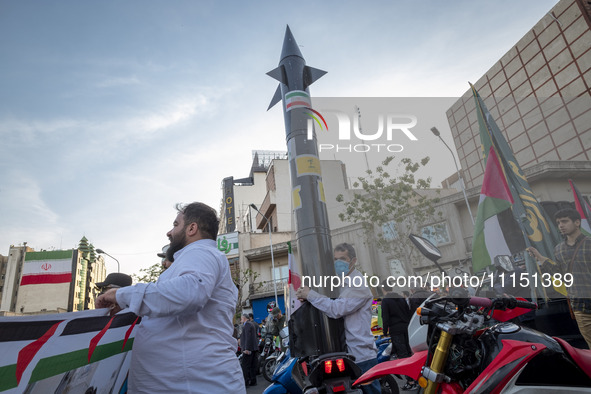 An unidentified man is holding a model of Iran's first-ever hypersonic missile, Fattah, during a gathering to celebrate the IRGC UAV and mis...