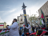 An unidentified man is holding a model of Iran's first-ever hypersonic missile, Fattah, during a gathering to celebrate the IRGC UAV and mis...