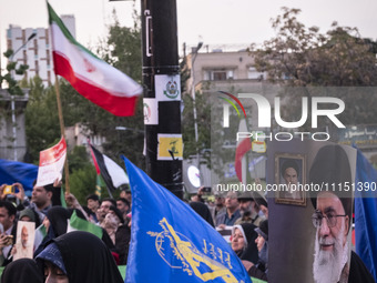 Veiled women are waving the flag of the Islamic Revolutionary Guard Corps and holding a portrait of Iran's Supreme Leader, Ayatollah Ali Kha...