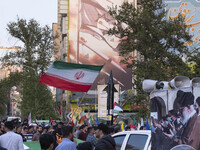 A man is waving an Iranian flag next to a model of Iran's first-ever hypersonic missile, Fattah, under an anti-Israeli mural during a gather...