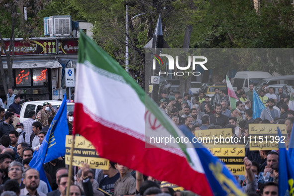 A man is waving an Iranian flag in front of a model of Iran's first-ever hypersonic missile, Fattah, during a gathering to celebrate the IRG...