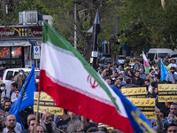 A man is waving an Iranian flag in front of a model of Iran's first-ever hypersonic missile, Fattah, during a gathering to celebrate the IRG...