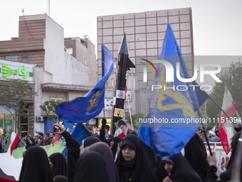 Veiled women are waving Iranian flags and flags of the Islamic Revolutionary Guard Corps while a model of Iran's first-ever hypersonic missi...