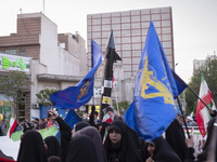 Veiled women are waving Iranian flags and flags of the Islamic Revolutionary Guard Corps while a model of Iran's first-ever hypersonic missi...