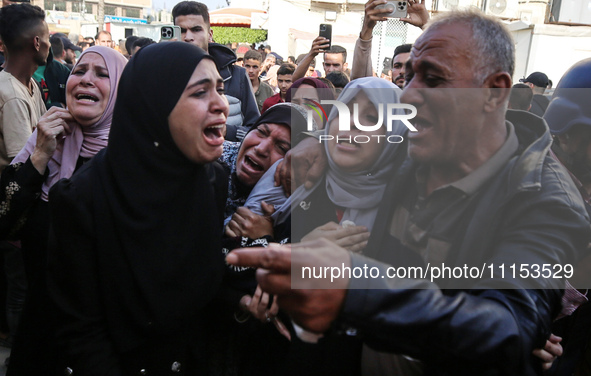 Palestinians are reacting next to their relatives who have been killed in an Israeli strike as they arrive at Al-Aqsa hospital, amid the ong...