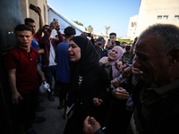 Palestinians are reacting next to their relatives who have been killed in an Israeli strike as they arrive at Al-Aqsa hospital, amid the ong...