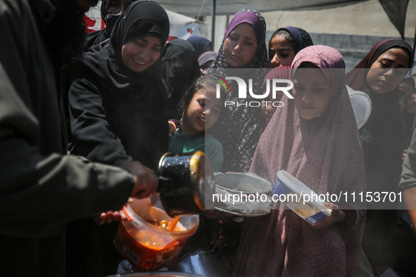 Displaced Palestinians are receiving cooked food rations at a donation point in Deir al-Balah in the central Gaza Strip, on April 16, 2024,...