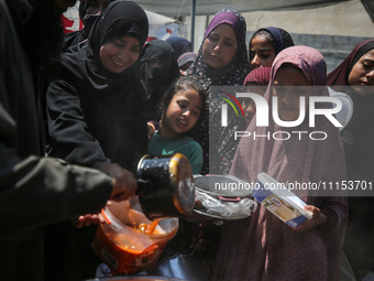 Displaced Palestinians are receiving cooked food rations at a donation point in Deir al-Balah in the central Gaza Strip, on April 16, 2024,...