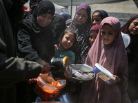 Displaced Palestinians are receiving cooked food rations at a donation point in Deir al-Balah in the central Gaza Strip, on April 16, 2024,...