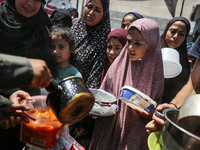 Displaced Palestinians are receiving cooked food rations at a donation point in Deir al-Balah in the central Gaza Strip, on April 16, 2024,...