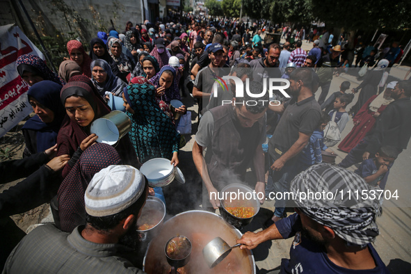 Displaced Palestinians are receiving cooked food rations at a donation point in Deir al-Balah in the central Gaza Strip, on April 16, 2024,...