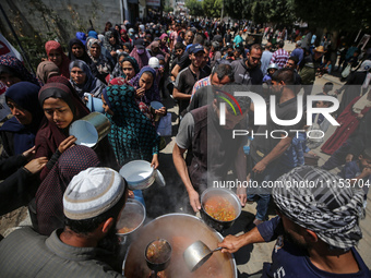 Displaced Palestinians are receiving cooked food rations at a donation point in Deir al-Balah in the central Gaza Strip, on April 16, 2024,...