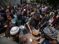 Displaced Palestinians are receiving cooked food rations at a donation point in Deir al-Balah in the central Gaza Strip, on April 16, 2024,...