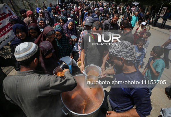 Displaced Palestinians are receiving cooked food rations at a donation point in Deir al-Balah in the central Gaza Strip, on April 16, 2024,...