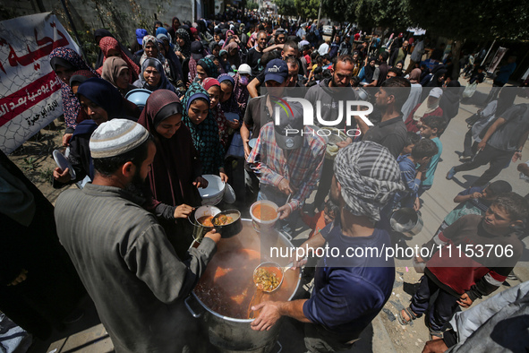 Displaced Palestinians are receiving cooked food rations at a donation point in Deir al-Balah in the central Gaza Strip, on April 16, 2024,...