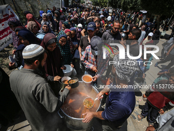 Displaced Palestinians are receiving cooked food rations at a donation point in Deir al-Balah in the central Gaza Strip, on April 16, 2024,...