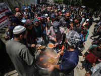 Displaced Palestinians are receiving cooked food rations at a donation point in Deir al-Balah in the central Gaza Strip, on April 16, 2024,...