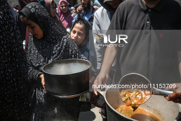 Displaced Palestinians are receiving cooked food rations at a donation point in Deir al-Balah in the central Gaza Strip, on April 16, 2024,...